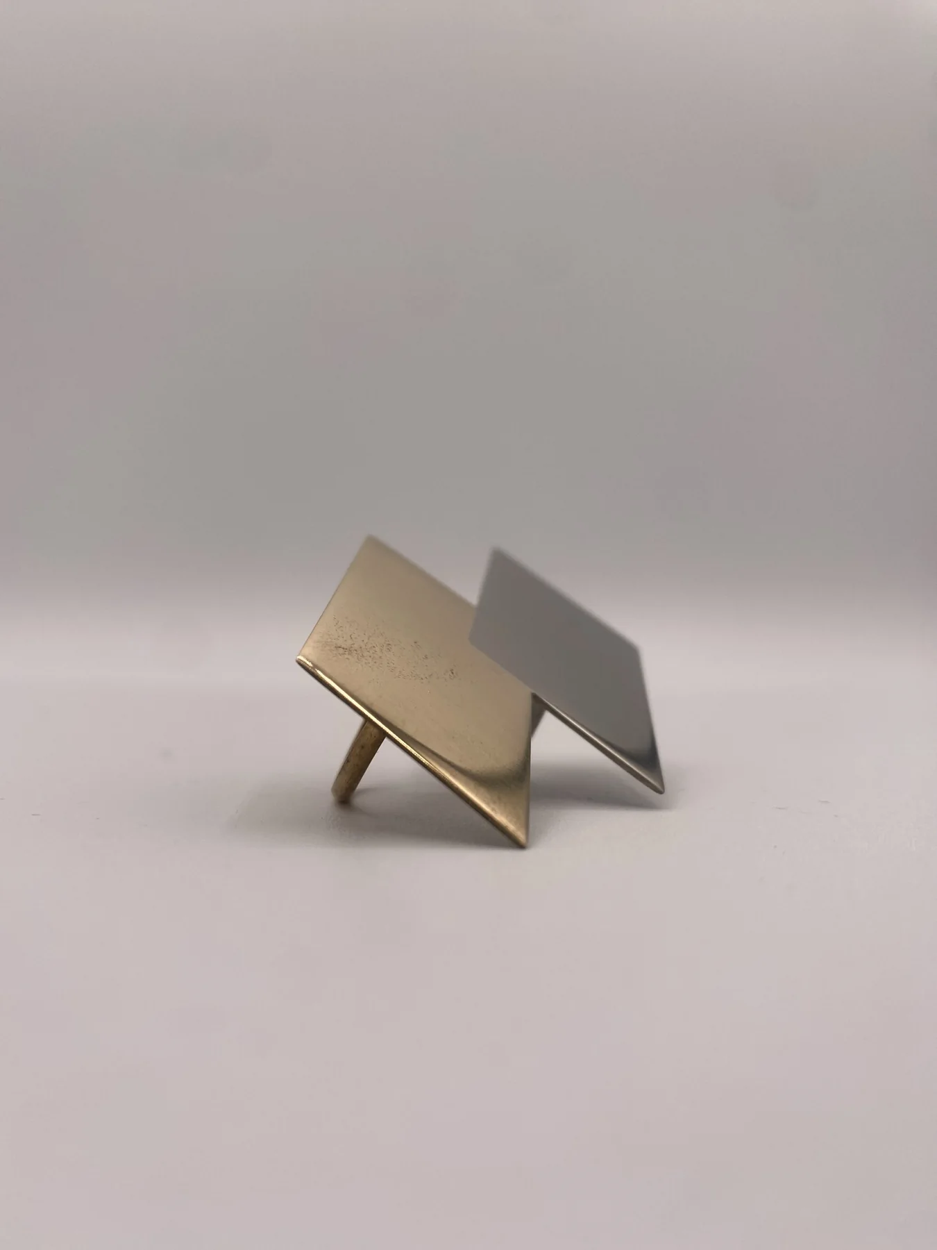 Two folded geometric forms displayed on a light surface.