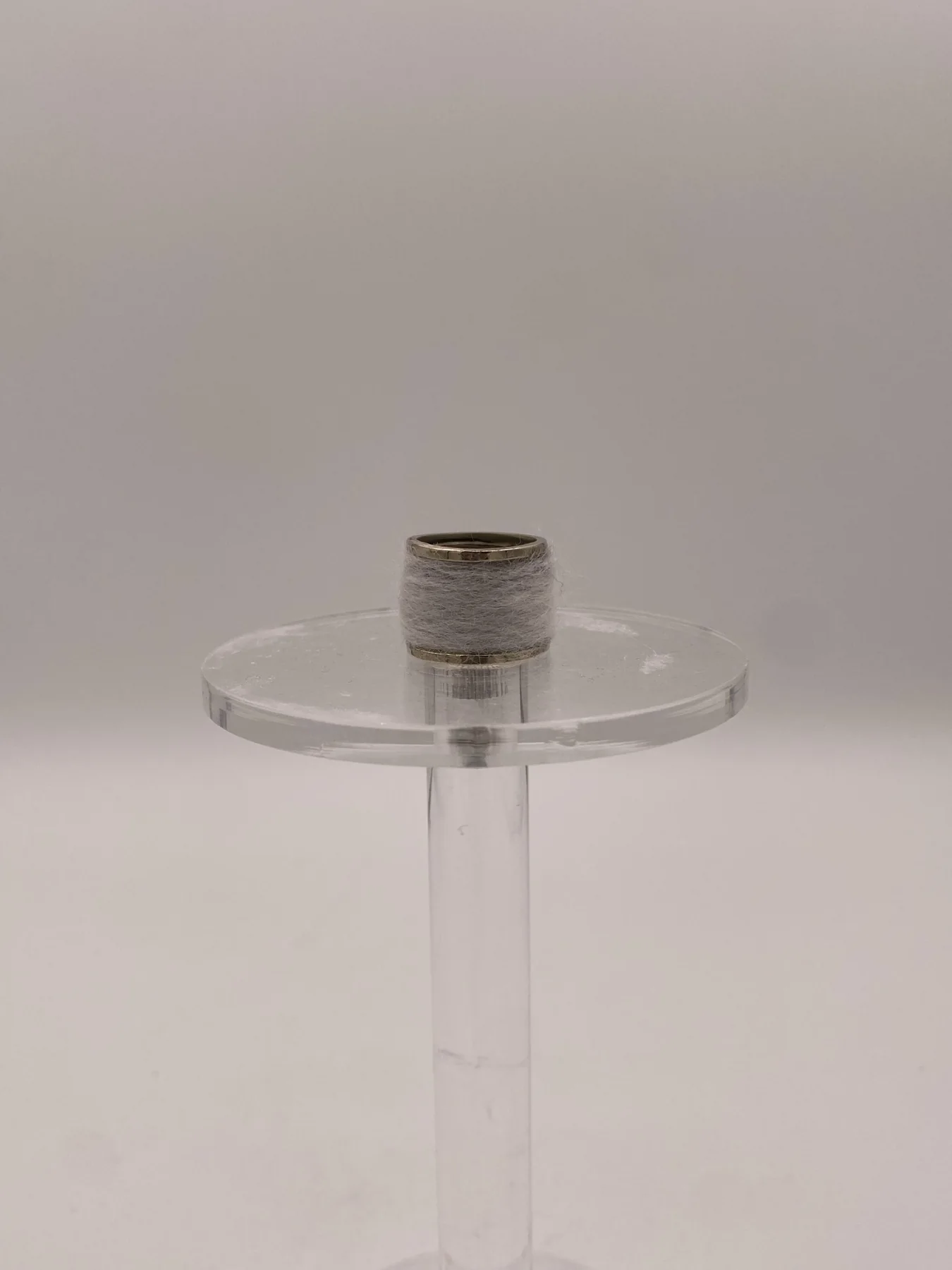 Textured band ring shown from the side on a clear stand.