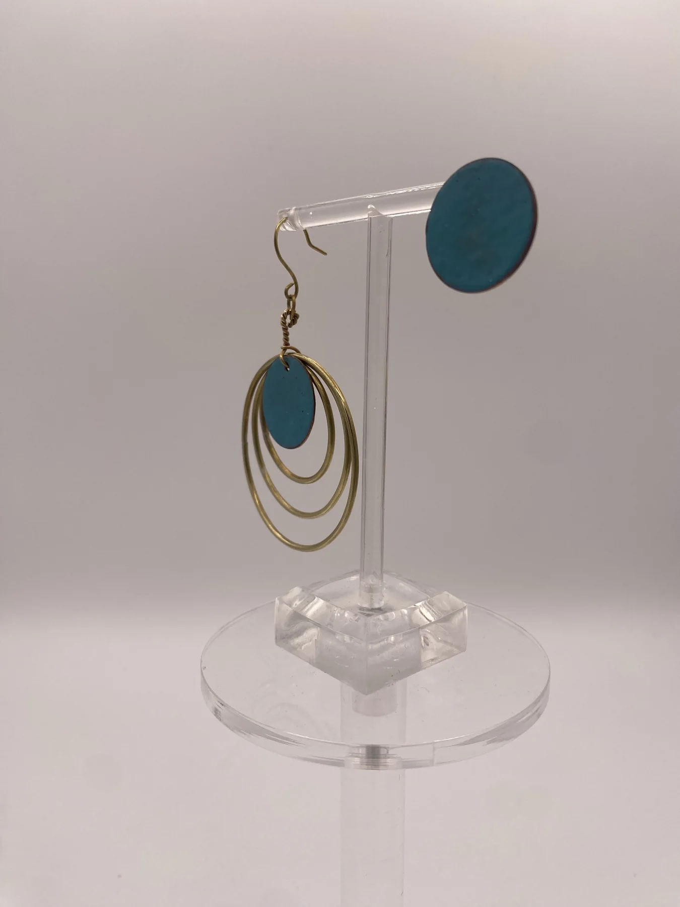 Side view of circular drop earrings on a display stand.