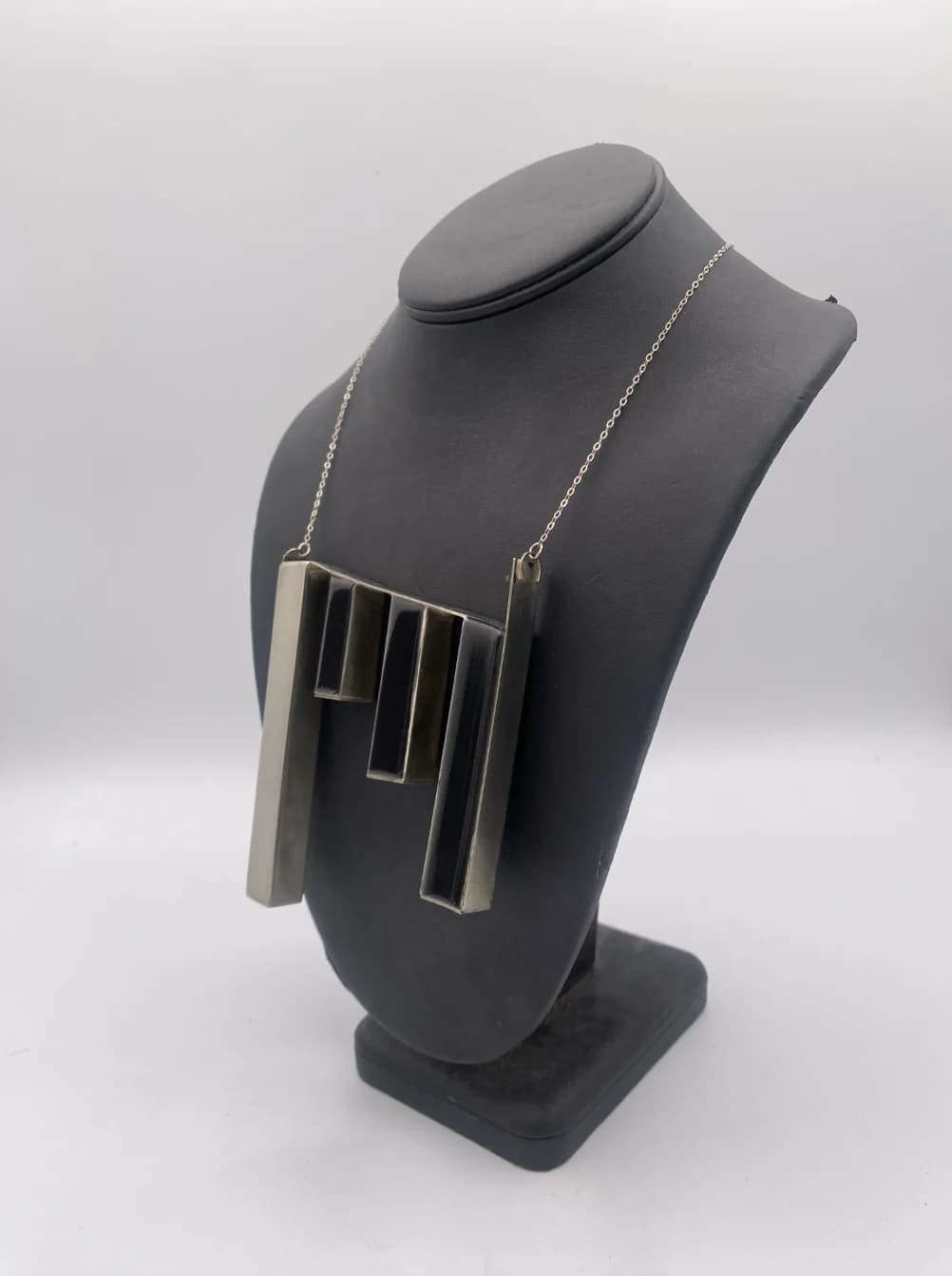 Sculptural pendant necklace displayed on a dark bust.